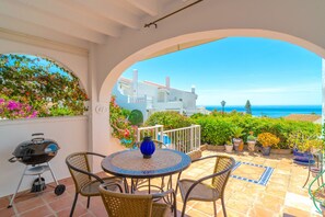 Pihalla on pyöreä pöytä ja tuolit, grilli sekä ruukuissa olevia kasveja.