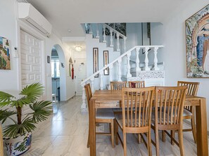 Ein Essbereich mit einem Holztisch und Stühlen, einer Treppe und einer Topfpflanze.