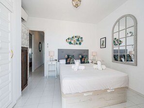 Ein Schlafzimmer mit Bett, Nachttischen, einem Spiegel und einer Wanddekoration.