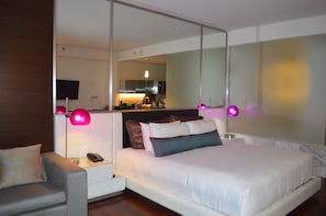 A bedroom with a bed, bedside tables, a nightstand, a lamp, and a mirror. - Cozy Studio in Hotel in Fabulous Las Vegas with Jetted Bathtub (Las Vegas)