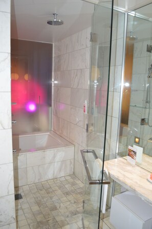 Un baño moderno con cabina de ducha de vidrio, bañera y suelo de mármol.
