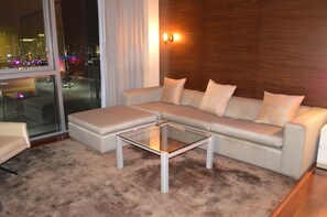 Una sala de estar moderna con un sofá modular, una mesa de centro de vidrio y vistas a la ciudad a través de amplias ventanas.