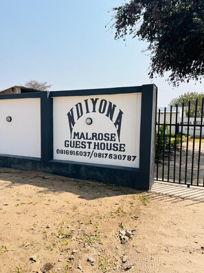 Letrero que indica 'INDYONA MALROSE GUEST HOUSE' con números de contacto.
