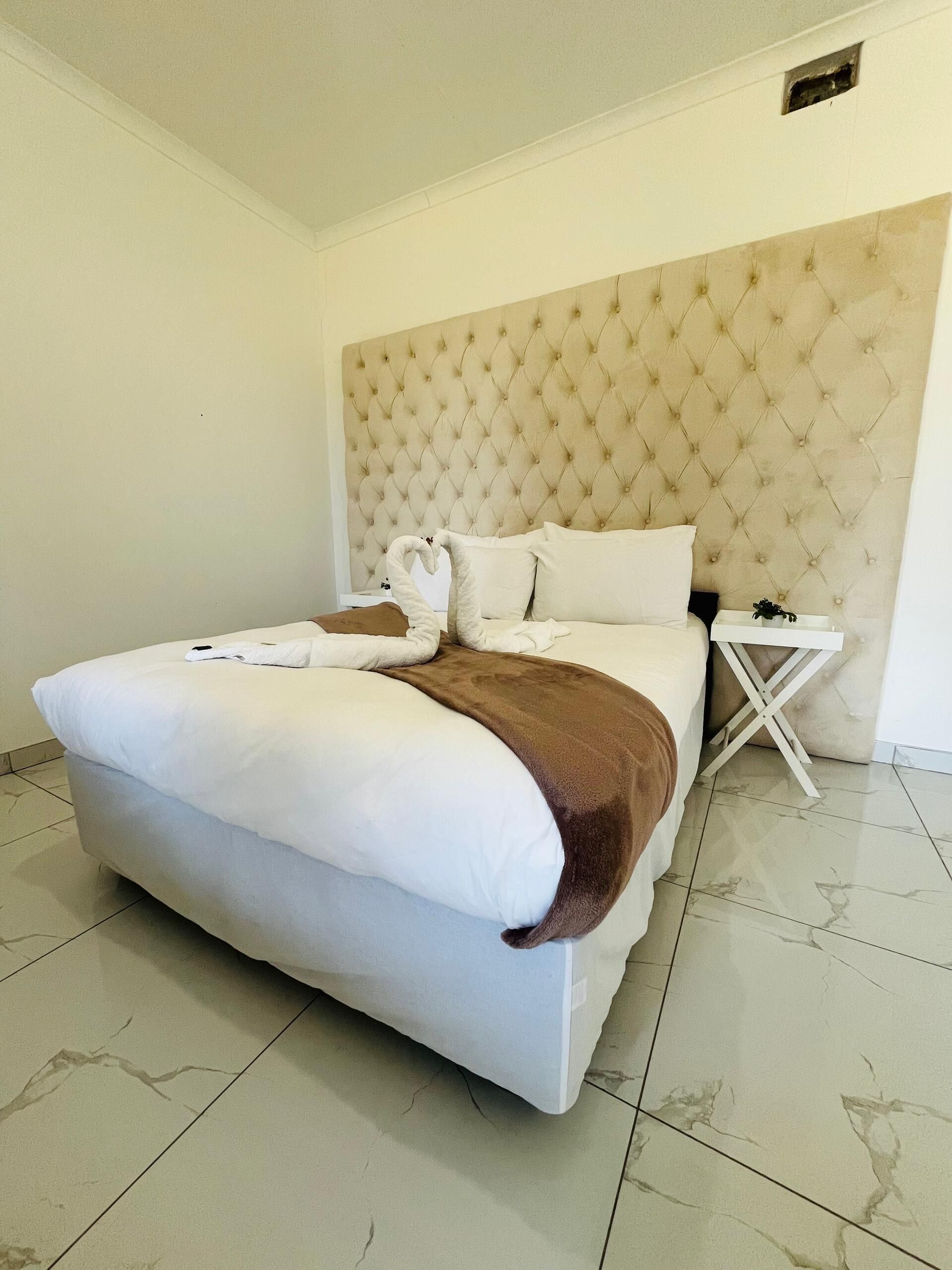 A hotel room with a large bed, a headboard, a bedside table, and a nightstand.