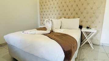 A hotel room with a large bed, a headboard, a bedside table, and a nightstand.