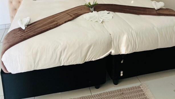 A bed with a tufted headboard, white bedding, and a brown throw blanket.