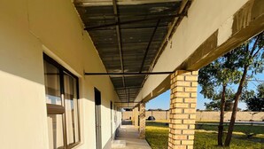 A covered corridor with a concrete floor, brick pillars, and a clear view of the outdoors.