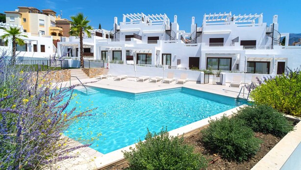 A poolside view of a resort with white buildings, a swimming pool, and surrounding greenery. - Villas de Punta Lara 18 by Casasol (Nerja)