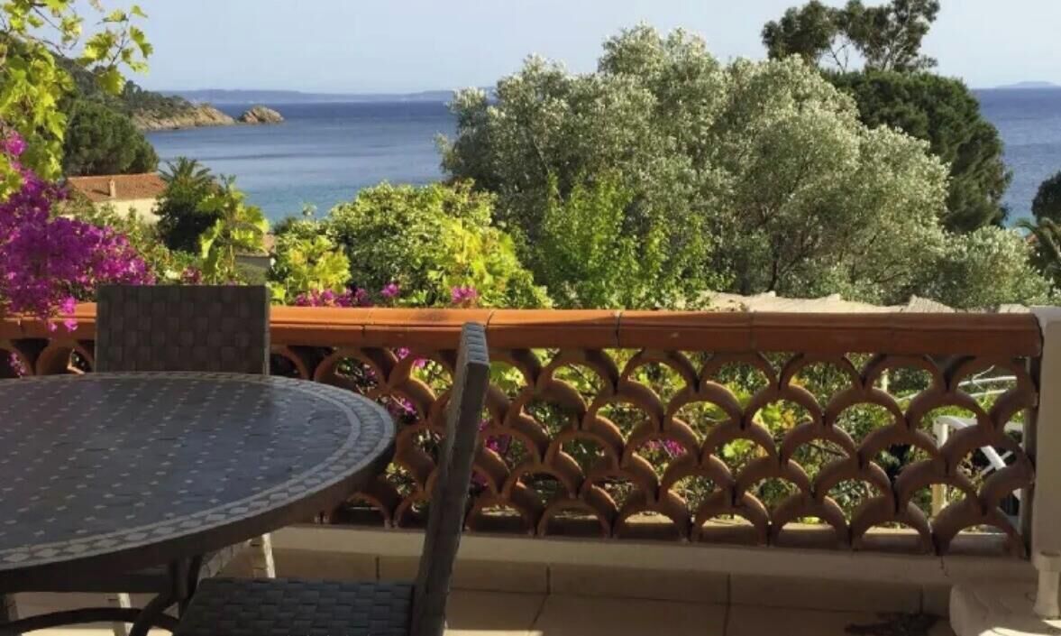 A balcony with a view of the sea, a round table, and a wooden lattice railing.