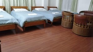 Een kamer met vier houten bedden, een rieten stoel en een houten tafel.