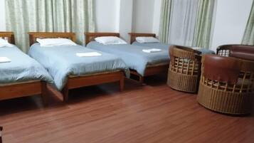 A room with four wooden beds, a wicker chair, and a wooden table.