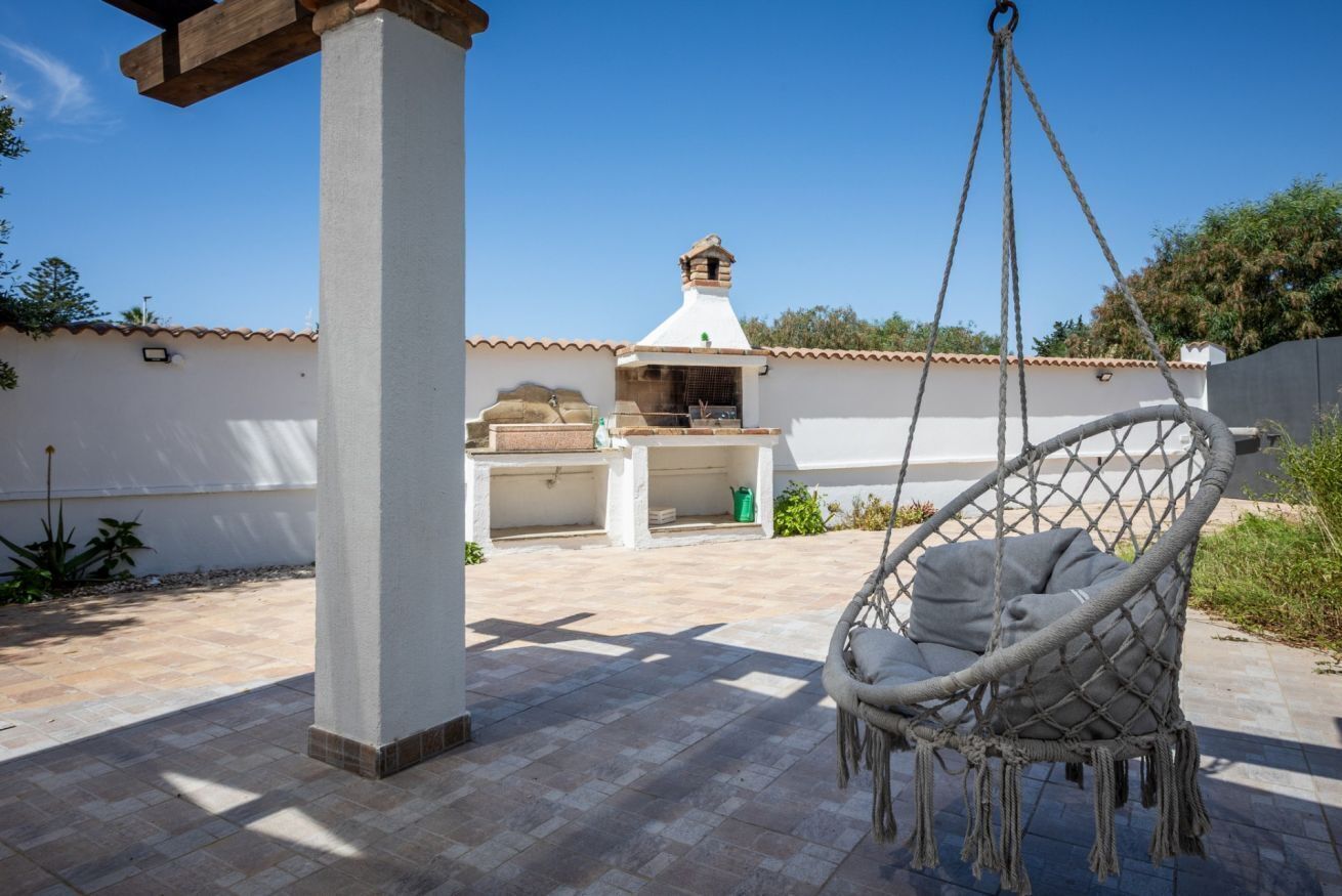 A patio with a hanging chair, a chimney, and a grill area.
