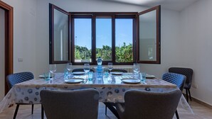 Ein Essbereich mit einem Tisch für sechs Personen, großen Fenstern und zwei Stühlen.