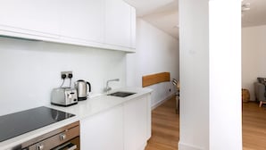Eine moderne Küche mit weißen Schränken, einer schwarzen Induktionskochplatte, einem Wasserkocher und einem Toaster.