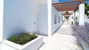 A modern building with a white exterior, a covered walkway, and lavender plants. - Villas de Punta Lara 18 by Casasol (Nerja)