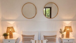 A neatly made bed with striped bedding, two bedside lamps, and two round mirrors on the wall. - Casa del Parque Tacoronte Centro (Tacoronte)