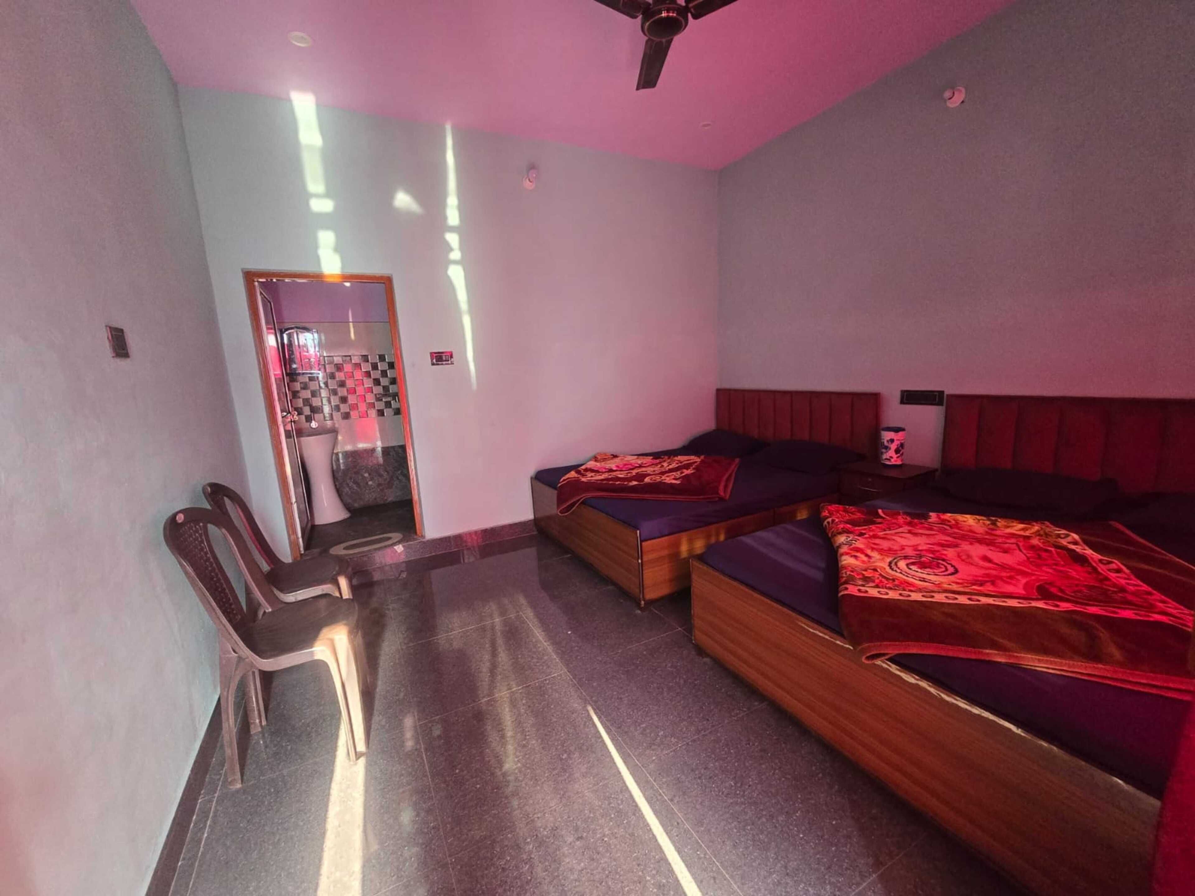A room with two beds, a chair, and a small table.