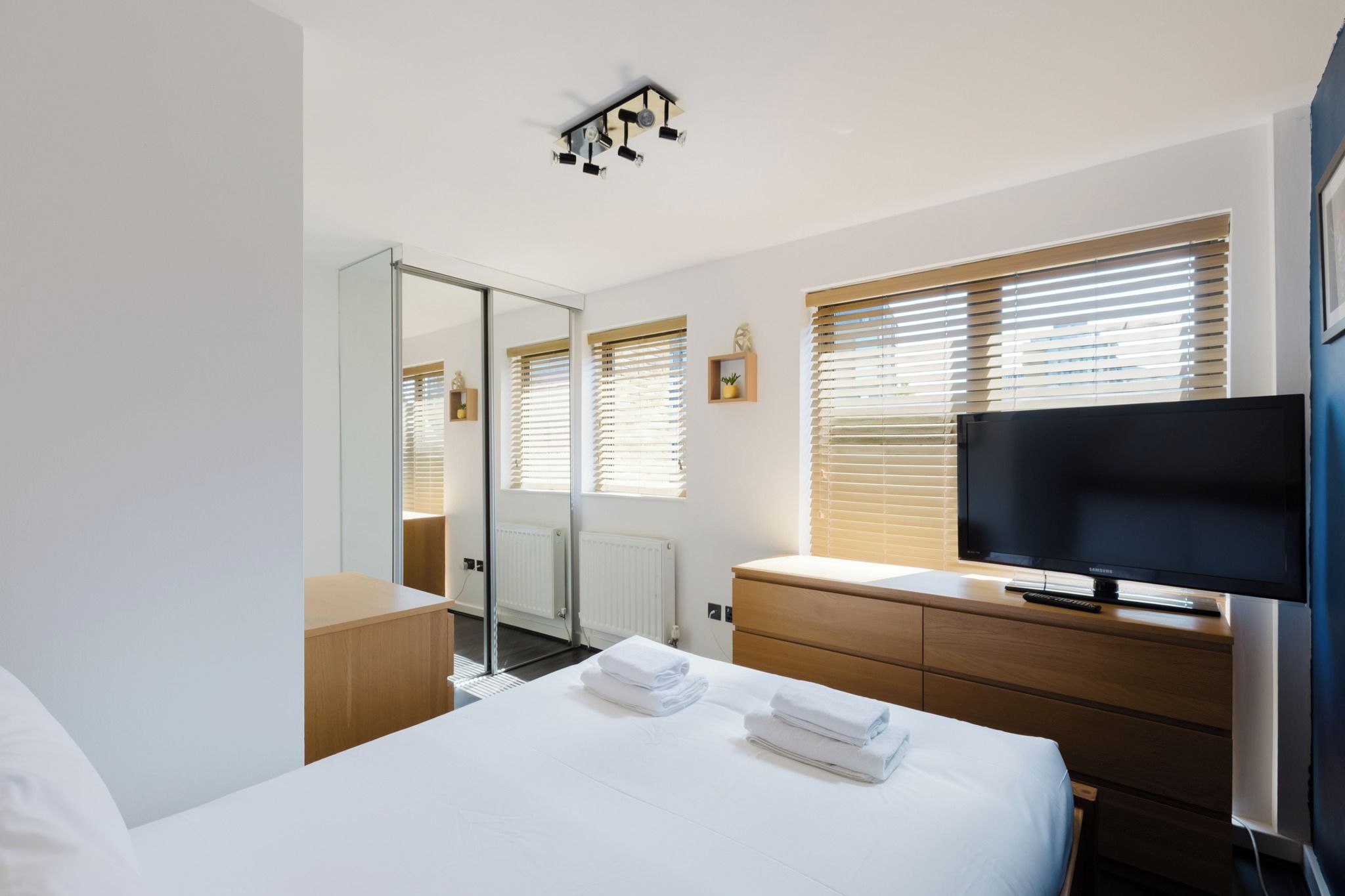 A hotel room with a bed, a television, a dresser, and a mirror.