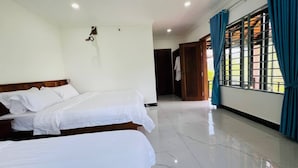 Habitación de hotel con dos camas, cabecera de madera, pared blanca, suelo de baldosas y ventana con cortinas azules.