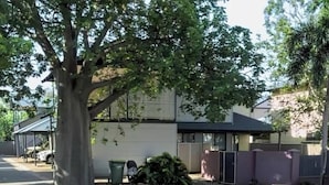 A residential property with a paved driveway, a covered carport, a large tree, and a small garden area. - Room-broome Rest House (Broome)