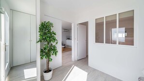 A modern interior with a potted plant, white walls, and a wooden floor. - Azur retreat High-End Seafront Apartment (Villeneuve-Loubet)