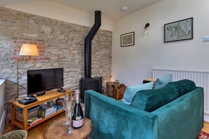 Ein gemütliches Wohnzimmer mit Steinwand, schwarzem Kamin, Fernseher, Sofa und Lampe.