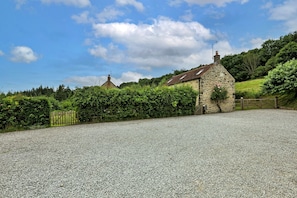 Ein Steinhaus mit Kiesweg und hölzernem Tor.