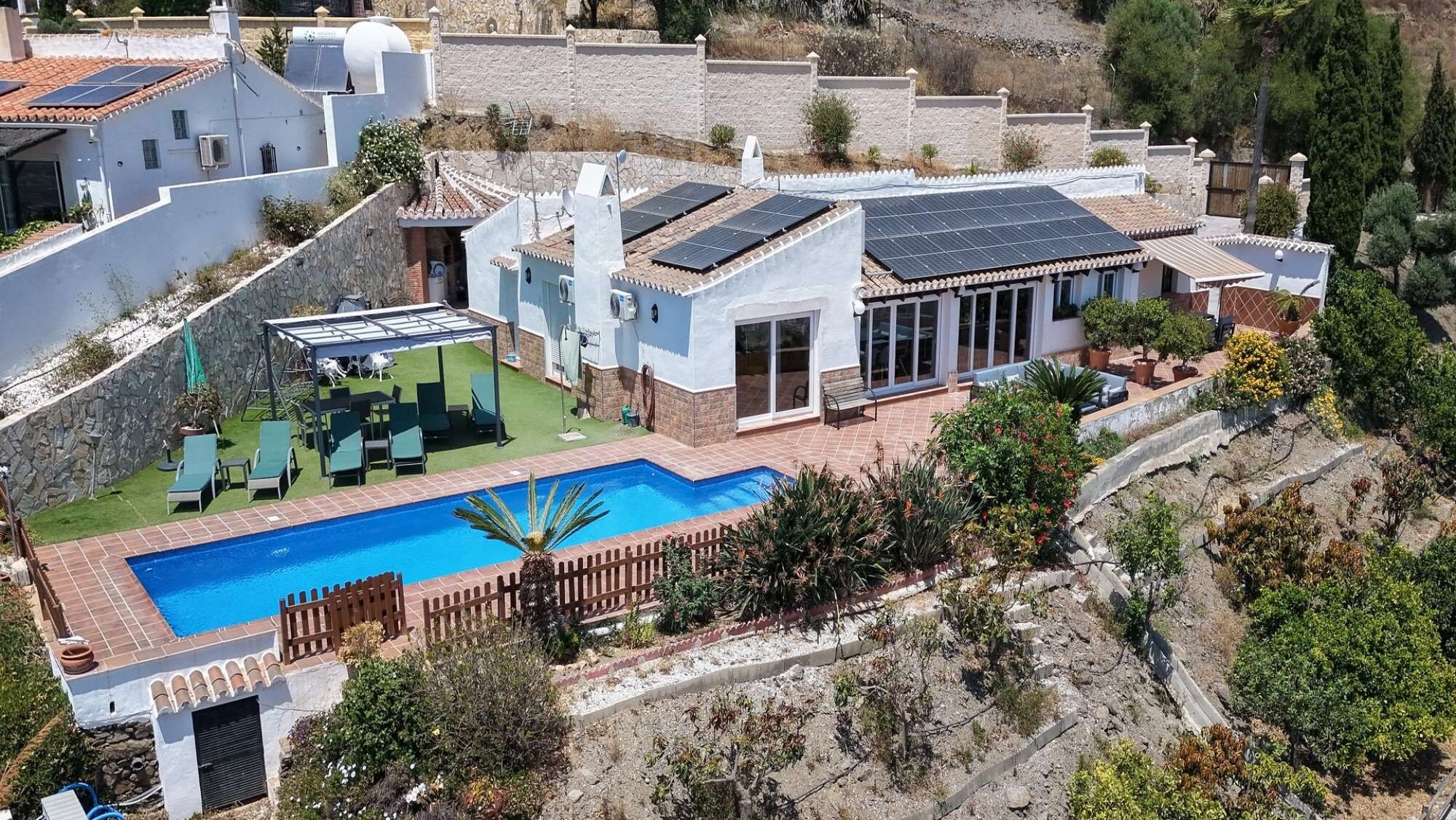A residential property with a swimming pool, solar panels, and a patio area.
