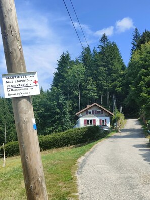 A rural road leading to a house with a signpost indicating distances to nearby locations. - the Clos des biches (Xonrupt-Longemer)