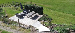 A wooden deck with outdoor furniture, a swing set, and a pathway leading to a grassy area. - the Clos des biches (Xonrupt-Longemer)