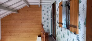 A wooden interior with a staircase, a wooden bench, and a wall with a forest pattern. - the Clos des biches (Xonrupt-Longemer)