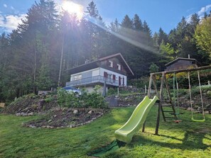 A residential area with a house, a green slide, and a swing set. - the Clos des biches (Xonrupt-Longemer)
