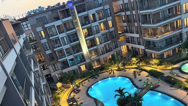 A multi-story residential building with a swimming pool and outdoor seating areas. - 1 bedroom apartment with splendour at Diamond in the City (Accra)