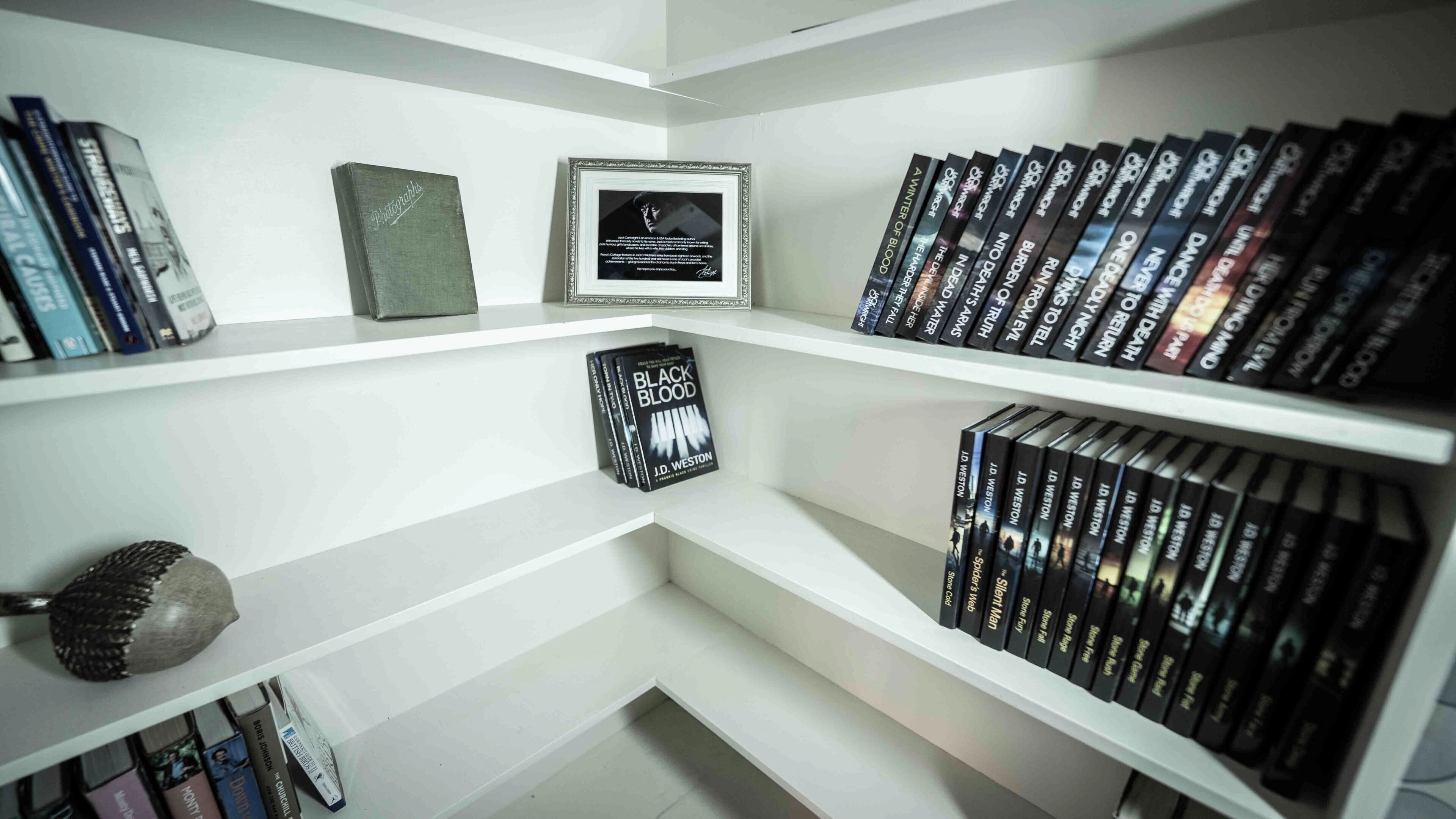 Una estantería con varios libros, una fotografía enmarco y una escultura decorativa de un pájaro.