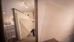Blick durch eine Tür in einen Raum mit Treppe und einer Theke, auf der Gegenstände stehen.