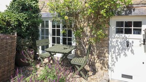 A garden with a table and chairs, a wicker basket, and a white door. - Freya's Cottage (Lincoln)