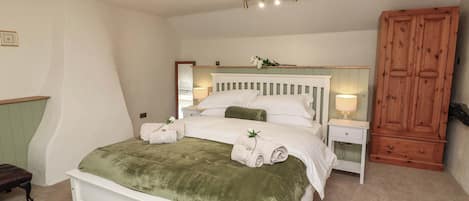 A bedroom with a bed, bedside tables, a wooden wardrobe, and a mirror.