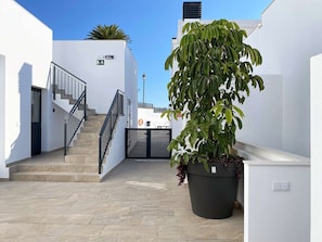 A clean, modern outdoor area with a staircase leading to a door, a large potted plant, and a clear blue sky. - Balcon del Mar Seaview 211 by Casasol (Nerja)