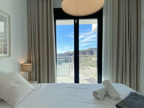 A hotel room with a bed, a lamp, and a view of a bridge and landscape through a large window. - Balcon del Mar Seaview 211 by Casasol (Nerja)