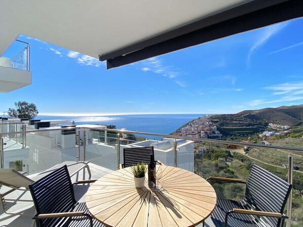 A balcony with a round wooden table, two chairs, and a potted plant. - Balcon del Mar Seaview 211 by Casasol (Nerja)