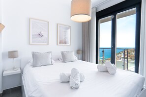 A hotel room with a large bed, two framed pictures on the wall, a window with a view of the sea, and a balcony. - Balcon del Mar Seaview 211 by Casasol (Nerja)