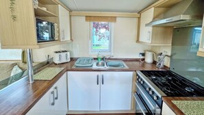 Een kleine keuken met een centraal eiland, ingebouwde apparatuur en een raam met uitzicht.