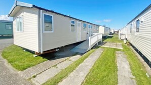 Een rijstaande vakantiehuisjes met een gazon ervoor en een verharde looppad.