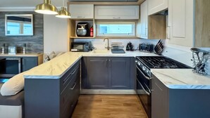 A compact kitchen with a central island, built-in appliances, and pendant lighting. - Swift Bordeaux Escape - UKC9640 (Towyn)