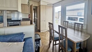 Une cuisine compacte comprenant un fourneau, des placards et un coin repas avec une table et des chaises.