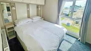 Une chambre d’hôtel avec un lit, un miroir, une fenêtre avec des rideaux et une vue sur l’extérieur.
