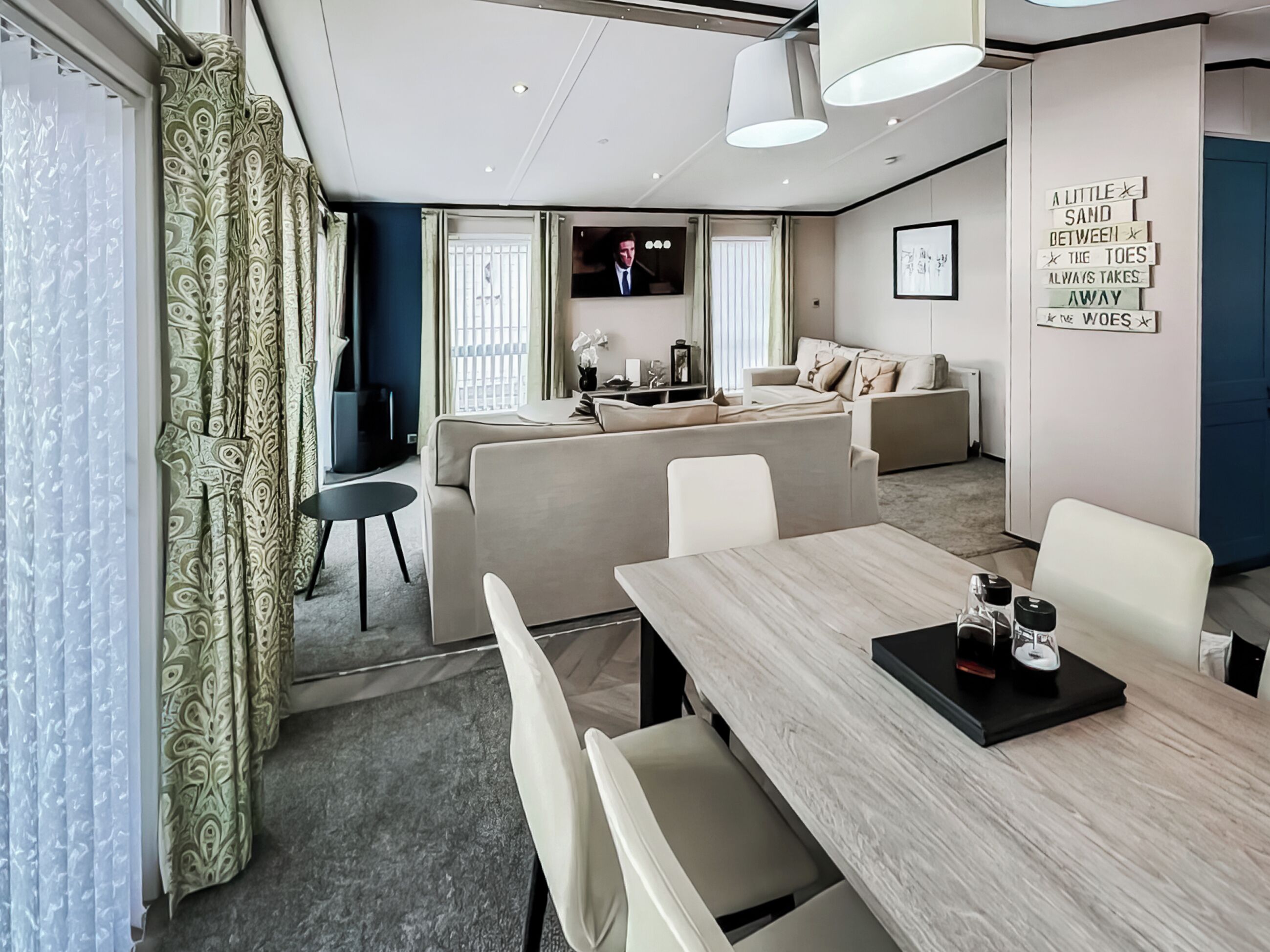 A modern hotel room with a dining area, sofa set, and a television.