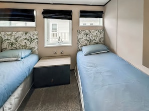 A bedroom with two beds, a window with a view, and a small table. - Monaco Duo - UKC9617 (Towyn)