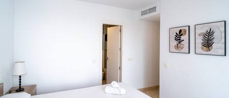 A hotel room with a bed, a nightstand, a lamp, and two wall art pieces.