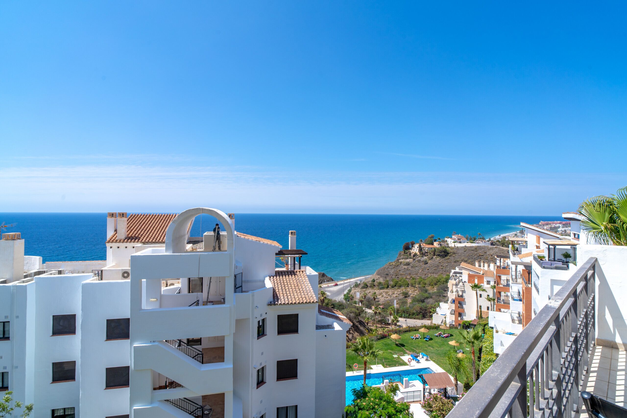Une vue sur la côte, avec des bâtiments blancs, un ciel bleu dégagé et une piscine bien visible.